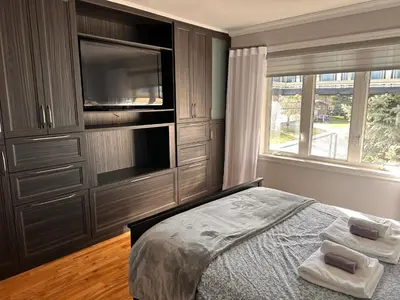 a bedroom with a bed and a tv and a window at Vieux Beloeil appartement free Parking in Beloeil Village