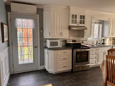 a kitchen with white cabinets and a stove top oven at Vieux Beloeil appartement free Parking in Beloeil Village
