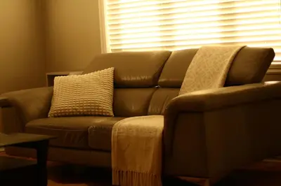 a brown leather couch in a living room with a window at Vieux Beloeil appartement free Parking in Beloeil Village