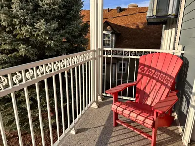 a red chair sitting on a porch next to a fence at Vieux Beloeil appartement free Parking in Beloeil Village