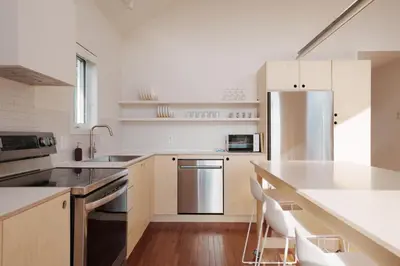 a white kitchen with a stainless steel refrigerator at Chalets OST Shefford FORFAIT GROUPE in Shefford
