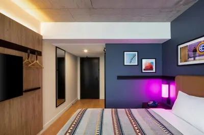 a bedroom with blue walls and a bed with purple lighting at Moxy Montreal Downtown in Montréal