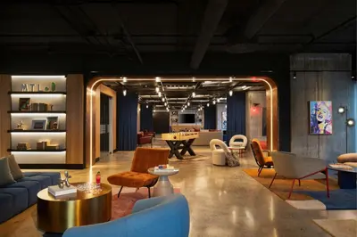 a living room with a blue couch and chairs at Moxy Montreal Downtown in Montréal