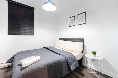 a white bedroom with a bed and a table at Bright stay in Griffin Town in Montréal