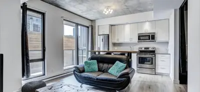a living room with a leather chair and a kitchen at INCh in Montréal