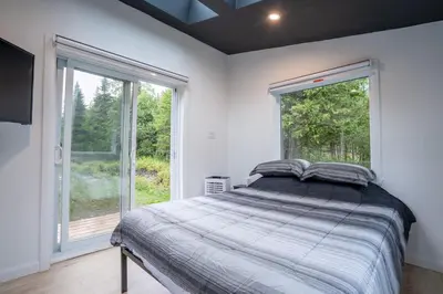 a bedroom with a bed and a large window at L'Étoile Brillante, Spa, River, Pool Table in La Patrie