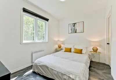 a white bedroom with a bed and a window at Chalet Escapade, Spa, Piscine in La Patrie