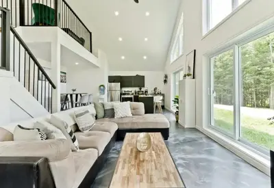 a living room with a couch and a table at Chalet Escapade, Spa, Piscine in La Patrie