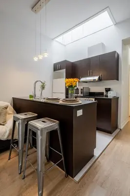 a kitchen with a counter with two stools and a sink at Cute Studio on Bishop - Hot Spot Dtown MTL in Montréal