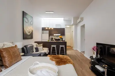 a living room with a couch and a kitchen at Cute Studio on Bishop - Hot Spot Dtown MTL in Montréal
