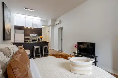 a living room with a couch and a kitchen at Cute Studio on Bishop - Hot Spot Dtown MTL in Montréal