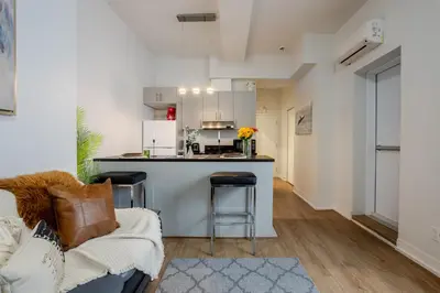 a living room with a couch and a kitchen at Snug Studio on Bishop DT MTL in Montréal