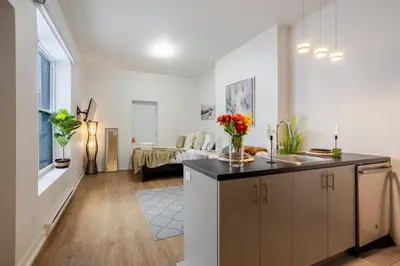 a kitchen and living room with a couch in the background at Snug Studio on Bishop DT MTL in Montréal