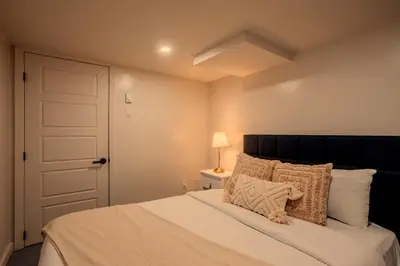 a bedroom with a bed with a black headboard and a door at Stylish 4BR in the heart of Plateau Montreal in Montréal