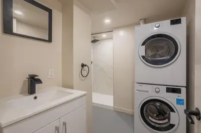 a white bathroom with a washing machine and a sink at Stylish 4BR in the heart of Plateau Montreal in Montréal