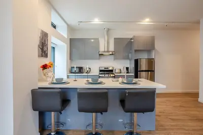 a kitchen with a island with three bar stools at Inner-City Studio on Bishop -Heart of MTL in Montréal