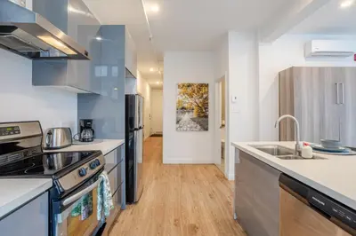 a kitchen with stainless steel appliances and wooden floors at Inner-City Studio on Bishop -Heart of MTL in Montréal