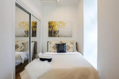 a bedroom with a bed with white sheets and a mirror at Inner-City Studio on Bishop -Heart of MTL in Montréal