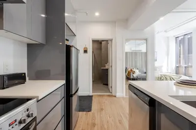 a kitchen with white countertops and a dining room at Modern Studio on Bishop - Spotlight MTL in Montréal