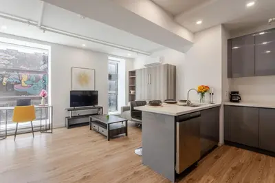 an open kitchen and living room with a large window at Modern Studio on Bishop - Spotlight MTL in Montréal