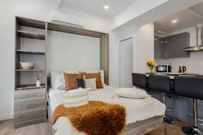 a bedroom with a large bed and a kitchen at Modern Studio on Bishop - Spotlight MTL in Montréal