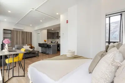 a bedroom with a white bed and a living room at Modern Studio on Bishop - Spotlight MTL in Montréal