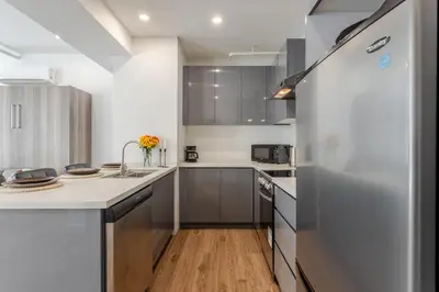 a kitchen with gray cabinets and a white refrigerator at Modern Studio on Bishop - Spotlight MTL in Montréal