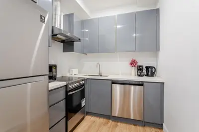 a kitchen with white cabinets and a stainless steel refrigerator at Apartment MTL Dtown Spotlight MTL in Montréal