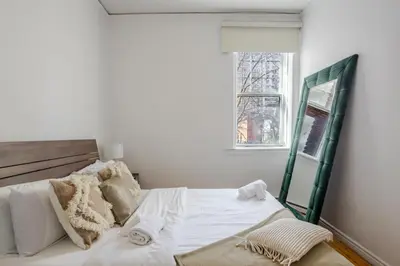 a white bed in a room with a window at Premium Location Stylish 3BR downtown Montreal in Montréal