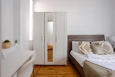 a white bedroom with a bed with a mirror at Premium Location Stylish 3BR downtown Montreal in Montréal