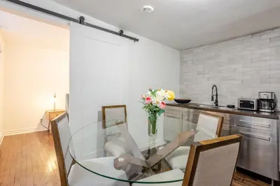 a glass dining room table with chairs and a vase of flowers at Artful 3BR in Montreal Village in Montréal
