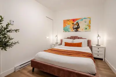 a bedroom with a large bed and a painting on the wall at Spacious 3BR in the heart of Village in Montréal