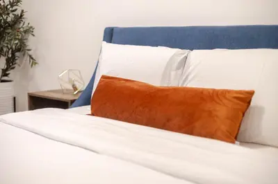 a white bed with a orange pillow on it at Spacious 3BR in the heart of Village in Montréal