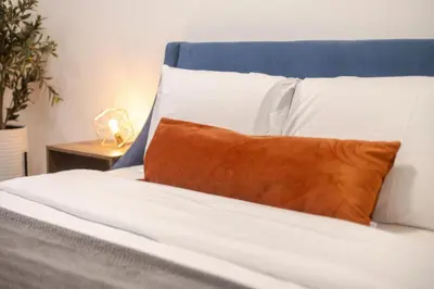 a blue and white bed with a orange pillow on it at Spacious 3BR in the heart of Village in Montréal