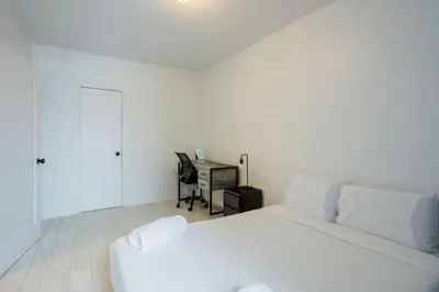 a white bedroom with a bed and a desk at Grand Urban 4BR Luxe Loft in Griffintown in Montréal