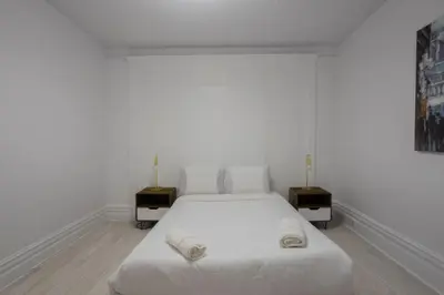 a white bedroom with a white bed and two night stands at Grand Urban 4BR Luxe Loft in Griffintown in Montréal