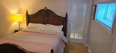 a bedroom with a large bed with a wooden headboard at The Home Sweet Home 20 Mnt away From Airport in Vaudreuil-Dorion
