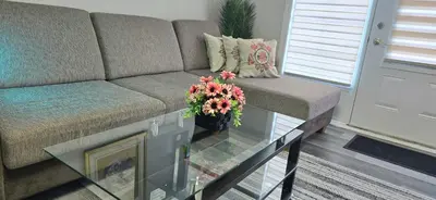 a living room with a couch and a glass table with flowers at The Home Sweet Home 20 Mnt away From Airport in Vaudreuil-Dorion