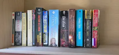 a row of books sitting on a shelf at The Home Sweet Home 20 Mnt away From Airport in Vaudreuil-Dorion