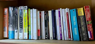 a row of books sitting on a shelf at The Home Sweet Home 20 Mnt away From Airport in Vaudreuil-Dorion