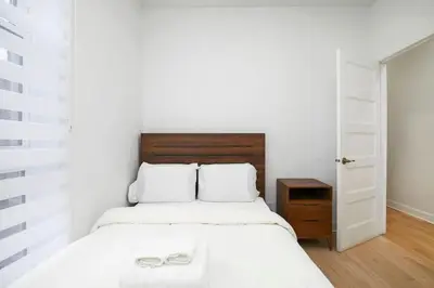 a bedroom with a white bed with a wooden headboard at Peaceful 2BR Getaway in Downtown in Montréal