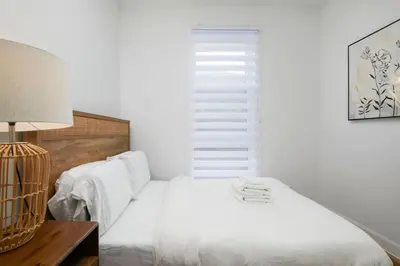a white bedroom with a bed and a window at Peaceful 2BR Getaway in Downtown in Montréal