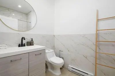 a bathroom with a white toilet and a mirror at Peaceful 2BR Getaway in Downtown in Montréal