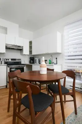 a kitchen with a wooden table and chairs and a kitchen with white cabinets at Peaceful 2BR Getaway in Downtown in Montréal