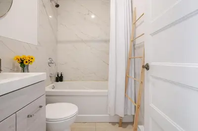 a white bathroom with a toilet and a bath tub at Outstanding 1BR village downtown MTL in Montréal