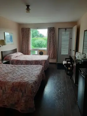 a hotel room with two beds and a window at Motel Vaudreuil in Vaudreuil-Dorion