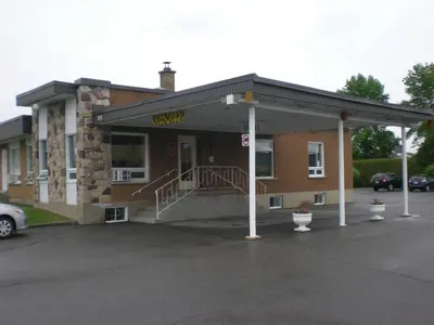 a building with a car parked in front of it at Motel Vaudreuil in Vaudreuil-Dorion