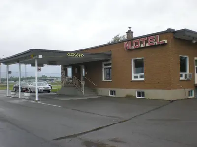 a mobil station with a car parked in a parking lot at Motel Vaudreuil in Vaudreuil-Dorion