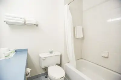 a white bathroom with a toilet and a shower at Motel Vaudreuil in Vaudreuil-Dorion