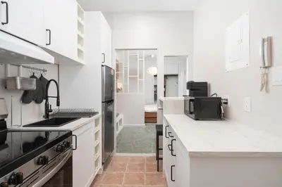 a kitchen with white cabinets and a stove top oven at Stylish loft in heart of Plateau in Montréal
